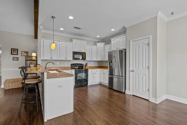 a kitchen with a refrigerator a sink dishwasher and a stove top oven with wooden floor