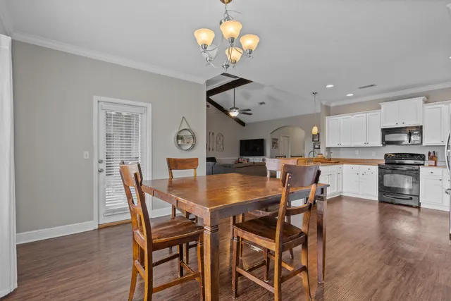 a dining room with wooden floor a chandelier a wooden table and chairs