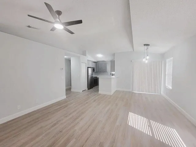 a view of a livingroom with a ceiling fan wooden floor and a ceiling fan