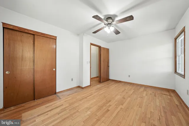 an empty room with wooden floor closet and windows