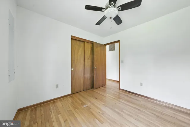 an empty room with a ceiling fan and wooden floor