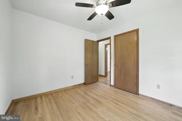 an empty room with wooden floor fan and windows