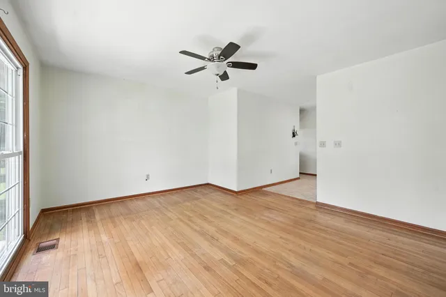a view of empty room with wooden floor and ceiling fan