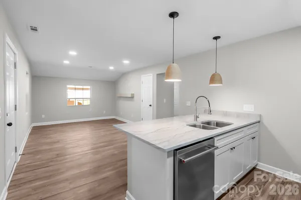 a kitchen with a sink chandelier and wooden floor