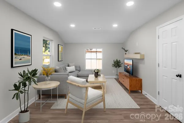 a living room with furniture a potted plant and a wooden floor