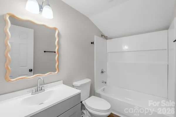 a bathroom with a bathtub shower sink vanity mirror and toilet