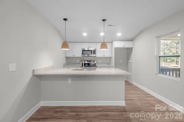 a view with kitchen island a sink wooden floor and a living room view