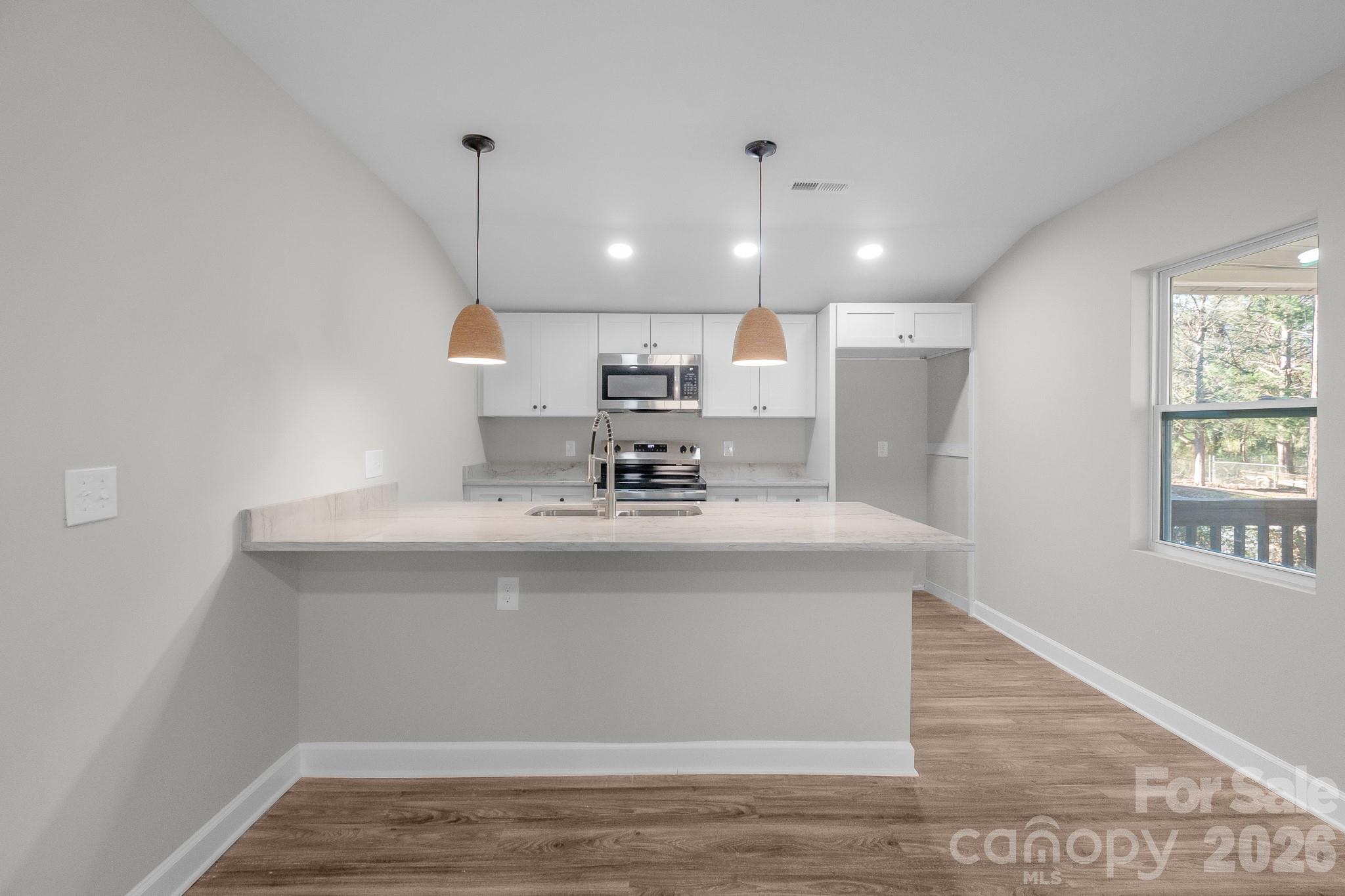 401 Golf Course Road Winnsboro, SC 29180 - Photo 7 of 39 a view with kitchen island a sink wooden floor and a living room view