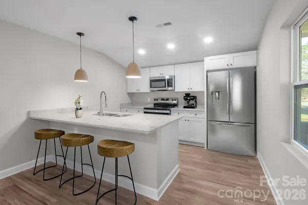 a kitchen with stainless steel appliances granite countertop a sink a stove a refrigerator and island with wooden floor