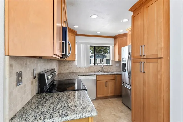 a kitchen with stainless steel appliances granite countertop a refrigerator sink and stove