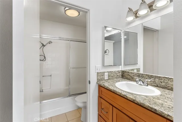 a bathroom with a granite countertop sink a toilet and shower