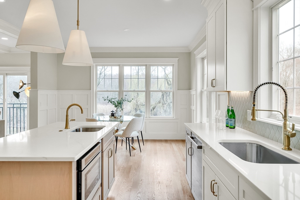 232 Lincoln Street Lexington, MA 02421 - Photo 6 of 41 a kitchen with a sink a counter and a dining table with wooden floor
