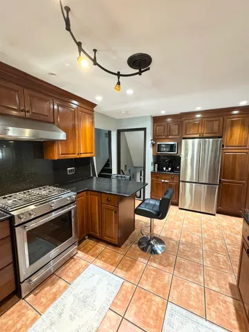 a kitchen with stainless steel appliances kitchen island granite countertop a stove and a sink