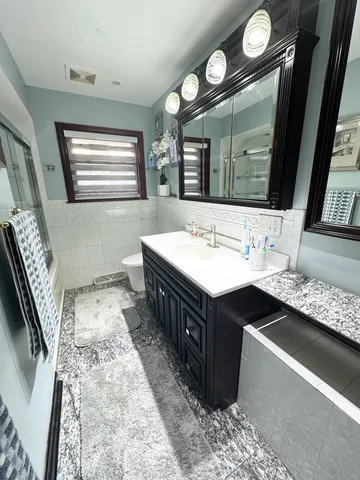 a bathroom with a double vanity sink mirror and bathtub
