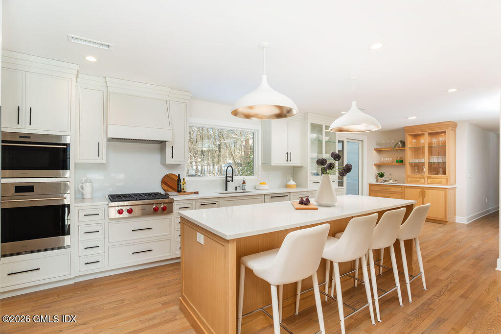 49 Salisbury Road Darien, CT 06820 - Photo 10 of 40 a kitchen with stainless steel appliances kitchen island granite countertop a stove a sink a dining table and chairs with wooden floor