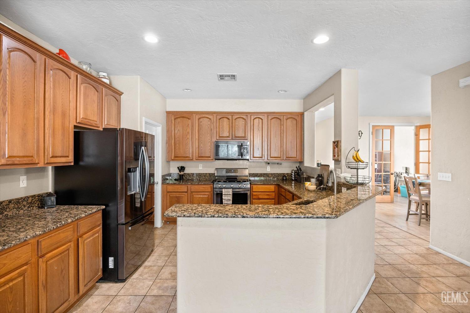 Undisclosed Address Bakersfield, CA 93313 - Photo 13 of 24 a kitchen with a refrigerator a stove a sink dishwasher and wooden cabinets with wooden floor