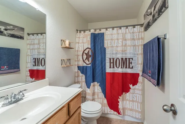 a bathroom with a sink a toilet and shower curtain