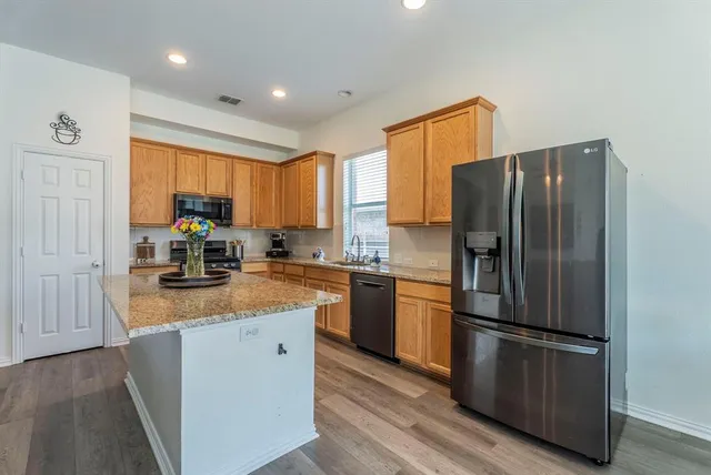 a kitchen with stainless steel appliances granite countertop a refrigerator a stove a sink dishwasher and a refrigerator with wooden floor