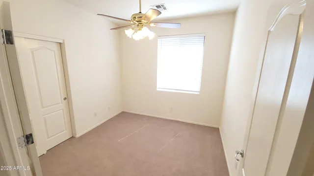 an empty room with windows and fan