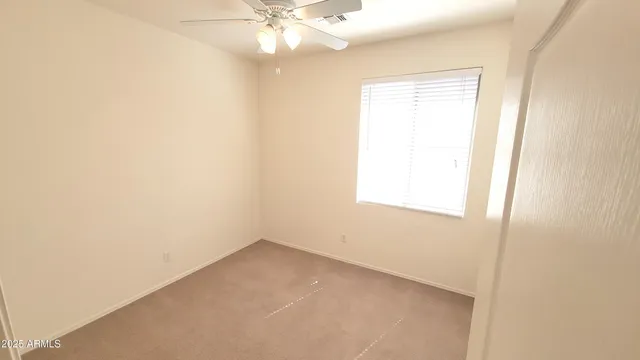 an empty room with a window and a fan