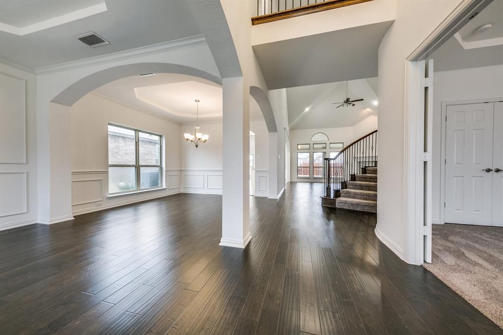 104 Sweetleaf Drive Red Oak, TX 75154 - Photo 18 of 36 Spacious interior featuring dark hardwood flooring, arched doorways, a grand staircase with wrought iron balusters, and large windows providing natural light
