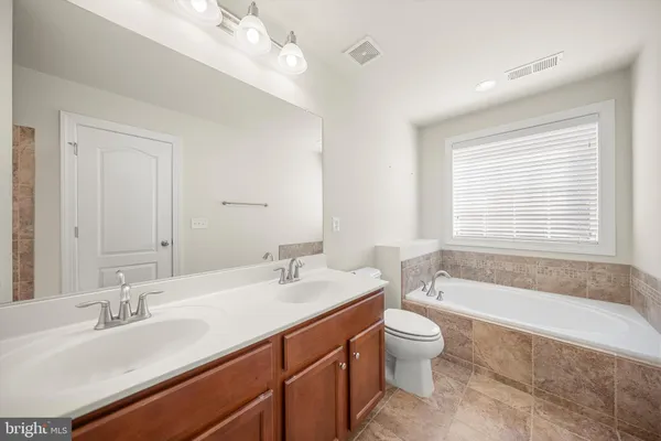 a bathroom with a double vanity sink toilet mirror and bathtub