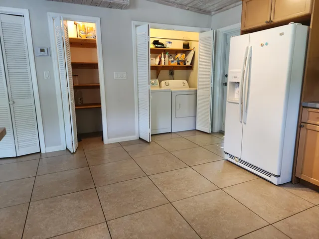 a view of a refrigerator in kitchen and an empty room with wooden floor windows