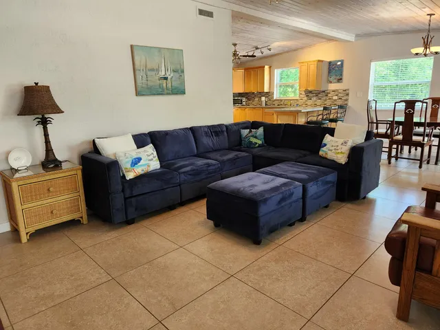 a living room with couches and kitchen view with wooden floor