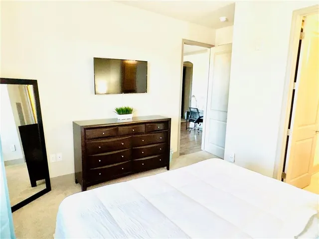 a bedroom with a bed and a flat tv screen on dresser