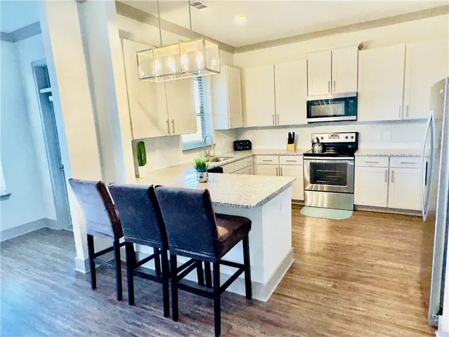 a kitchen with a stove a sink white cabinets and stainless steel appliances