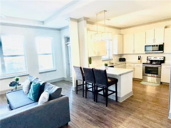 a living room with stainless steel appliances kitchen island granite countertop a stove a sink a dining table and chairs