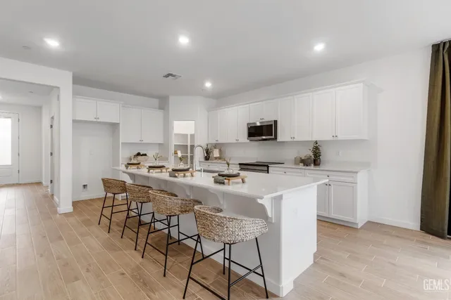 a kitchen with stainless steel appliances a sink a stove a refrigerator cabinets and a dining table