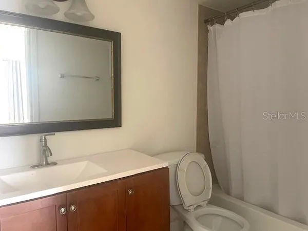 a bathroom with a granite countertop sink toilet and a mirror