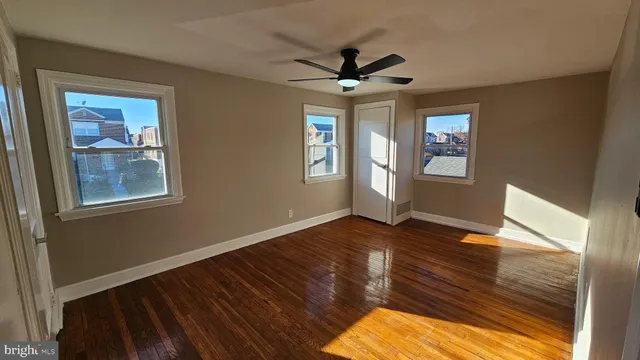 a view of empty room with wooden floor and fan