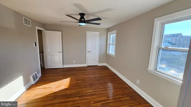 a view of empty room with wooden floor and fan
