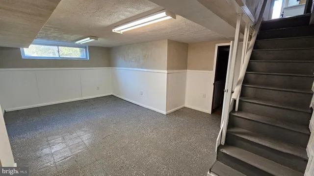 a view of an empty room with wooden floor and stairs