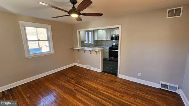 a view of an empty room with window and wooden floor