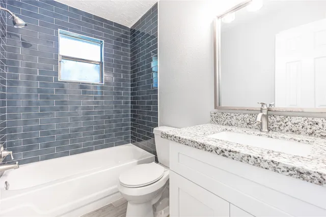 a bathroom with a granite countertop bathtub sink vanity mirror and toilet