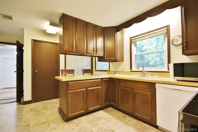 a kitchen with a sink cabinets stainless steel appliances and a window