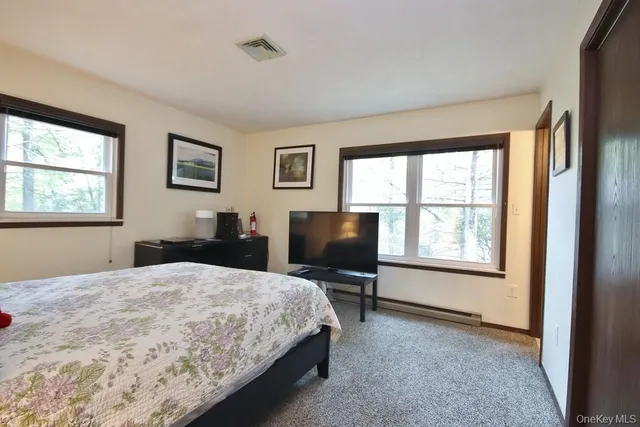 a bedroom with a bed computer on desk and a window
