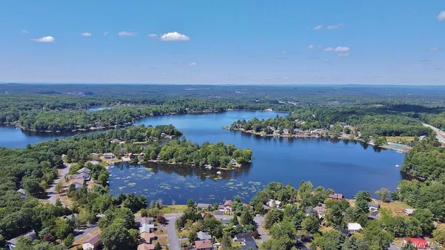 an aerial view of a houses with a yard and lake view