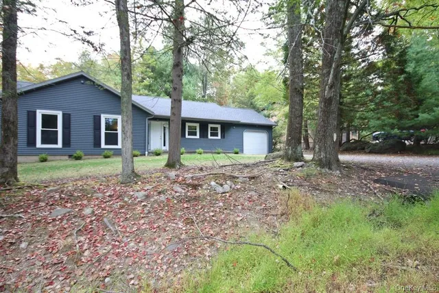 a view of a house with a yard and large trees