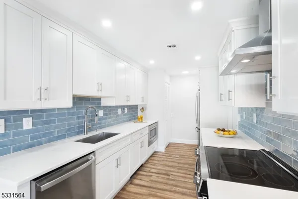 a large kitchen with stainless steel appliances a large counter top a stove and a sink