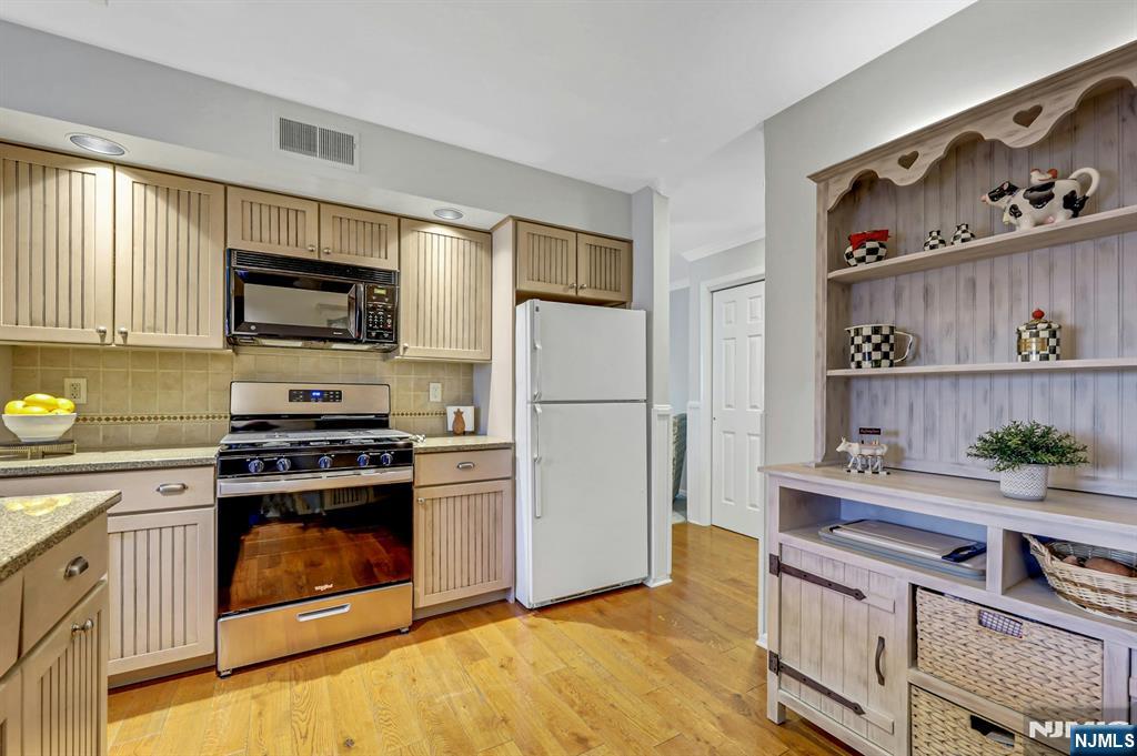 1712 Faulkner Court Mahwah, NJ 07430 - Photo 5 of 17 a kitchen with stainless steel appliances granite countertop a stove top oven a refrigerator and a cabinets with wooden floor