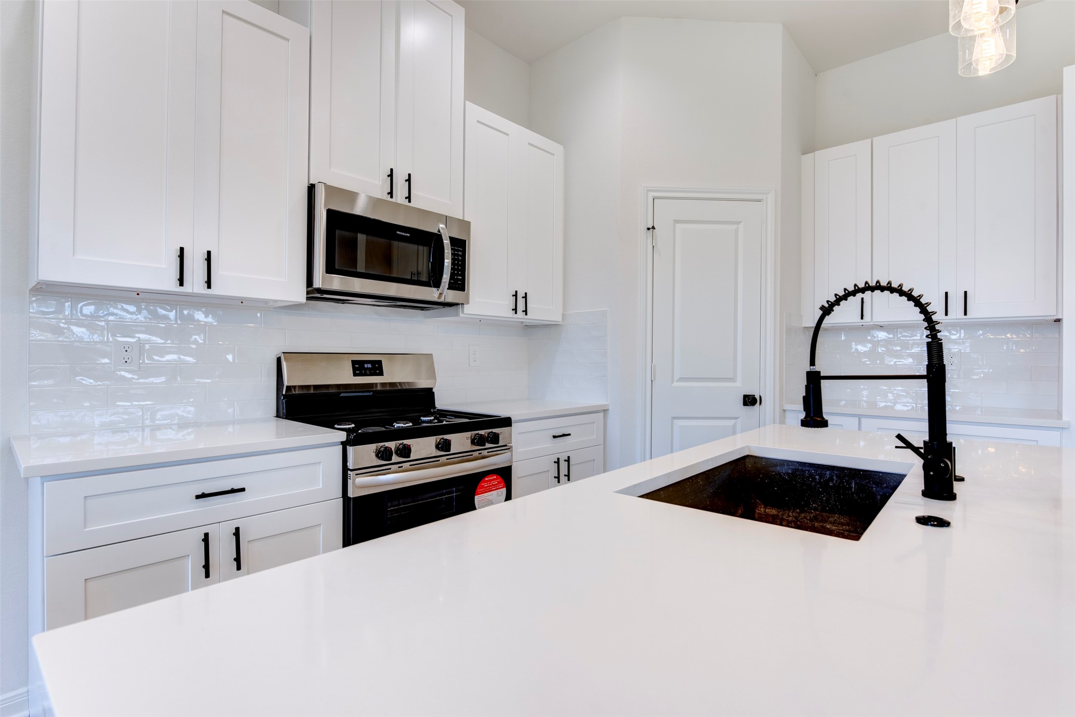 6809 Paris Street Houston, TX 77021 - Photo 10 of 37 Crisp kitchen design with quartz countertops, shaker cabinetry, and a glossy subway tile backsplash. Matte black fixtures and hardware add contrast, while stainless appliances and a spacious pantry keep the space both stylish and functional.