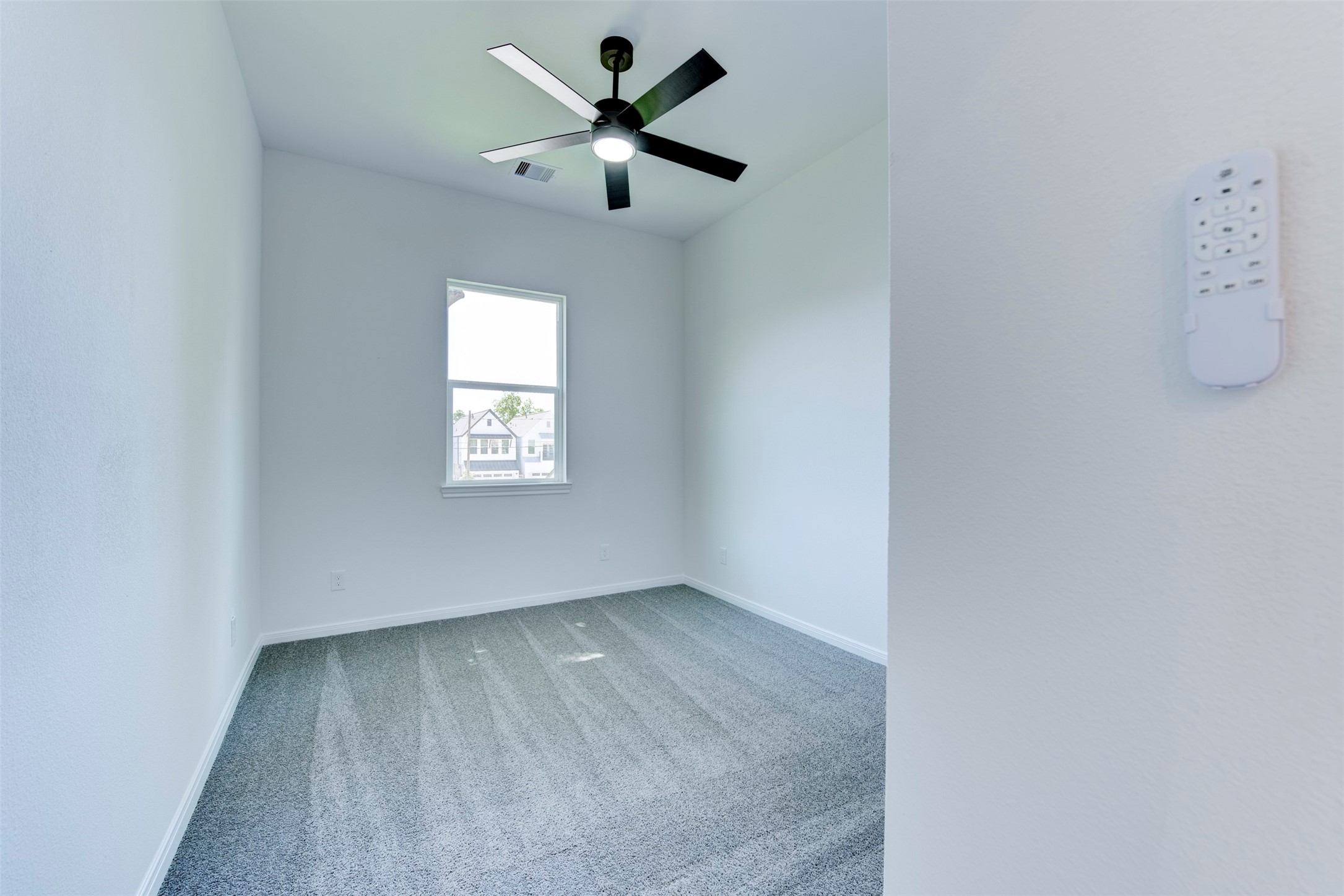 6809 Paris Street Houston, TX 77021 - Photo 20 of 37 Secondary bedroom with plush carpet, a ceiling fan with integrated light kit, and a large window bringing in natural light. Clean, neutral finishes create a bright and comfortable space.