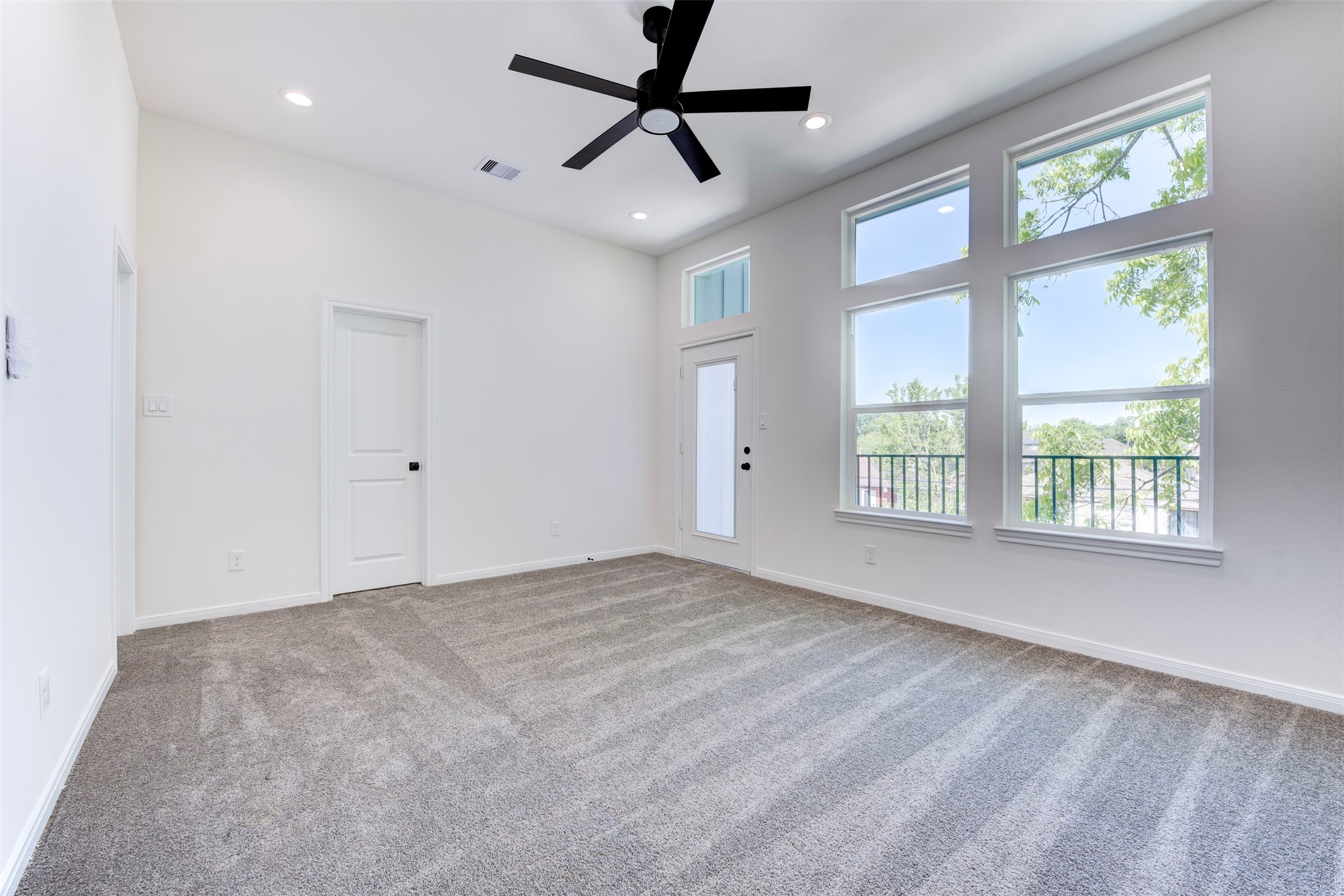 6809 Paris Street Houston, TX 77021 - Photo 25 of 37 Spacious primary suite featuring plush carpet, a ceiling fan with light kit, and recessed lighting throughout. Abundant natural light pours in through large windows, while direct access to a private balcony adds a peaceful, elevated retreat.