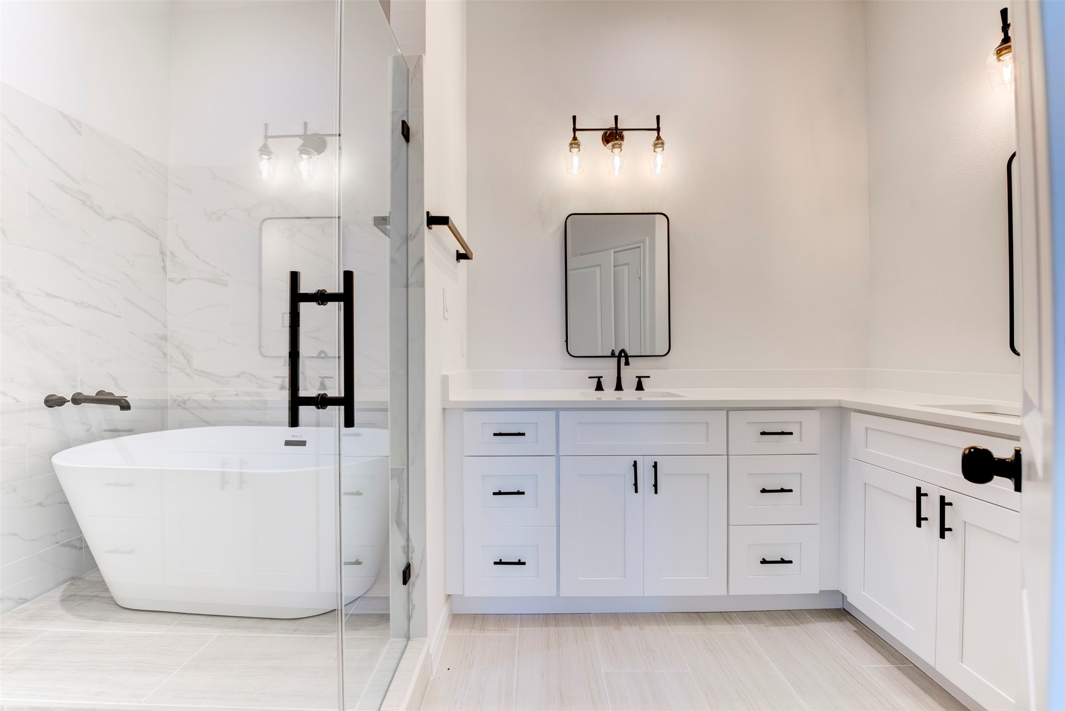 6809 Paris Street Houston, TX 77021 - Photo 28 of 37 Primary bath featuring a freestanding soaking tub set within the walk-in shower, creating a true spa-like retreat. Dual sink areas with separate vanities offer added functionality, all finished with quartz countertops, shaker cabinetry, and matte black fixtures.
