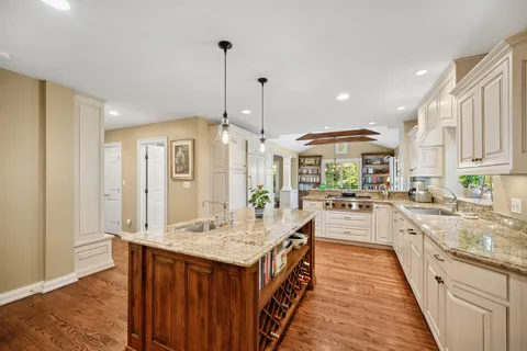 a large kitchen with kitchen island a large counter space a sink appliances and living room view
