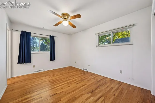 a view of an empty room with wooden floor and window